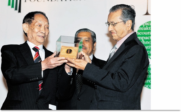 北京时间 2012 年 1 月 31 日晚 10 时 30 分，马来西亚前首相马哈蒂尔（右）在吉隆坡城中城国际会展中心为 “杂交水稻之父” 袁隆平（左）颁发 2011 年 “马哈蒂尔科学奖”，以表彰他为热带农业发展作出的杰出贡献。马哈蒂尔科学奖主要授予全球范围内通过科学技术解决热带各种问题作出贡献和革新的科学家、研究学术性机构及组织，奖金额为 10 万元马币（约合 20 万元人民币）。马哈蒂尔科学奖基金会颁奖给袁隆平院士的理由是：以独创性思维和胆识，在水稻这一热带主要作物的育种中冲破经典理论束缚，使杂交水稻这一创新性成果带来全球水稻生产及可持续性革命化的发展。（图片：张纹综/新华社）。